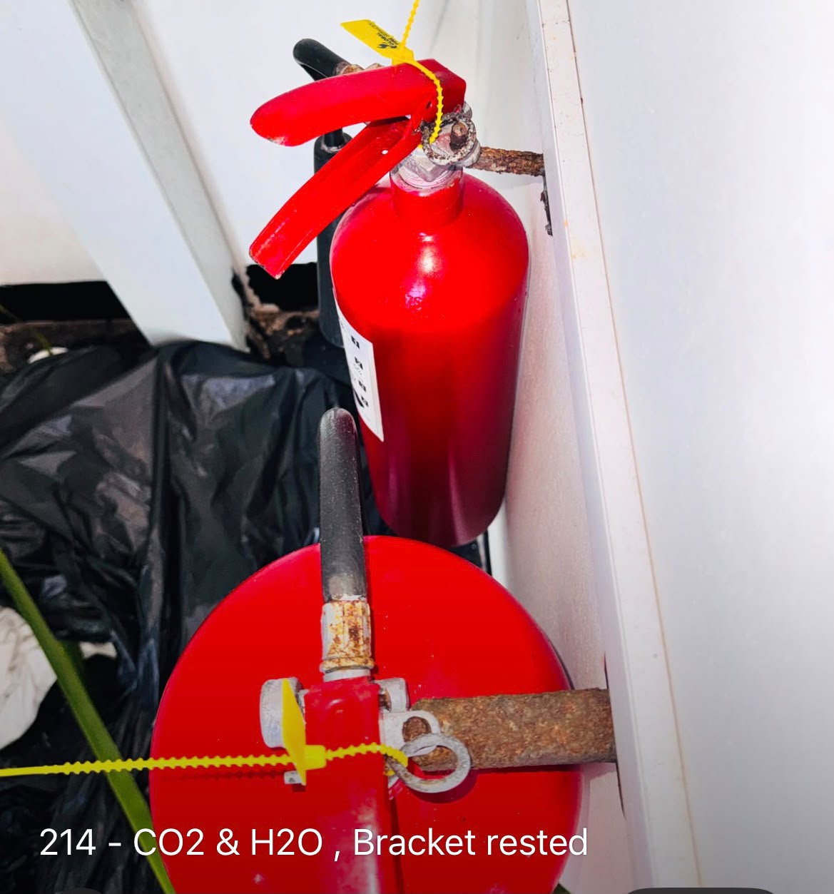 Two fire extinguishers on rusted wall brackets